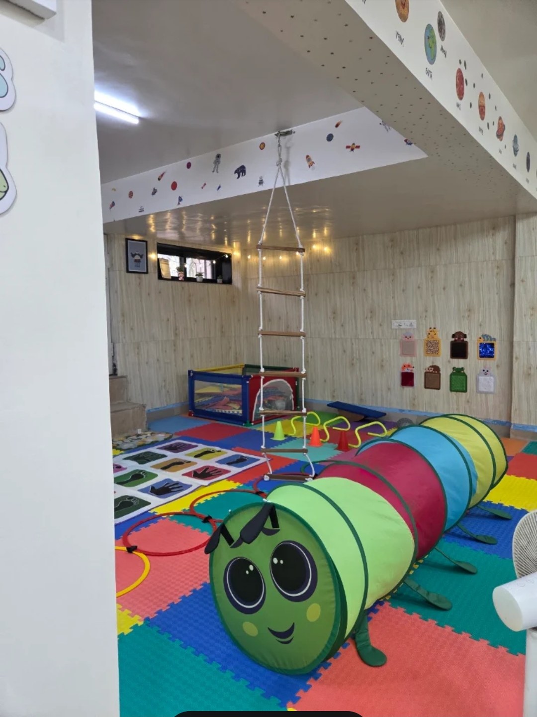 A colourful play tunnel and rope ladder in the sensory room